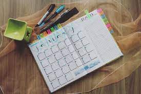 A calendar and diary placed side by side on a desk, symbolizing organization and planning.